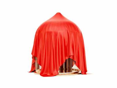 A gold bird cage draped by a red cloth.